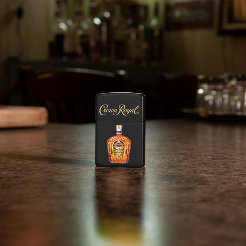 Lifestyle image of Zippo Crown Royal Logo and Bottle Black Matte Pocket Lighter standing on a bar.