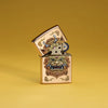 Lifestyle image of Zippo Foo Dog Design Brushed Brass Windproof Lighter standing in a golden scene.