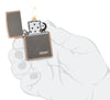Classic Rustic Bronze Zippo Logo Windproof Lighter lit in hand.