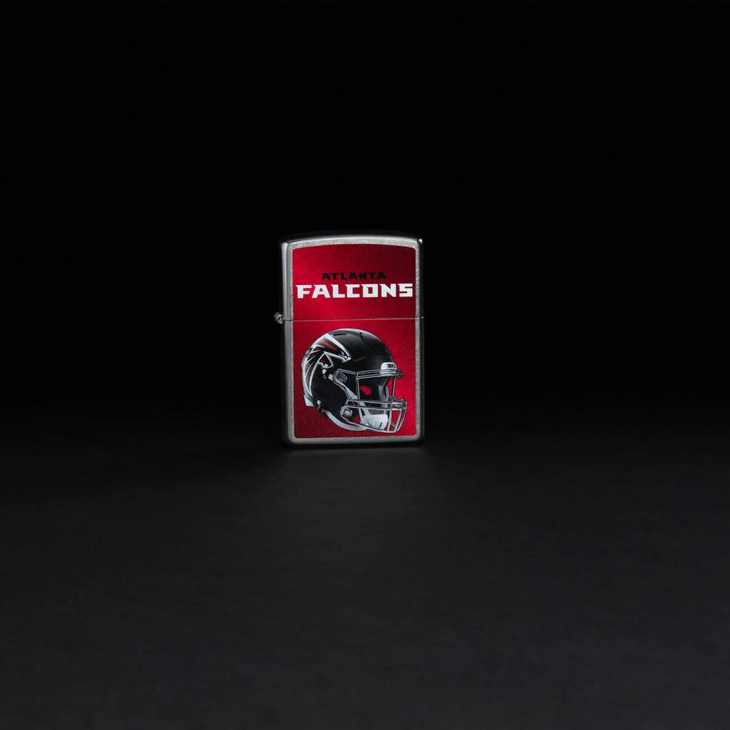 Lifestyle image of NFL Atlanta Falcons Helmet Street Chrome Windproof Lighter on a black background.