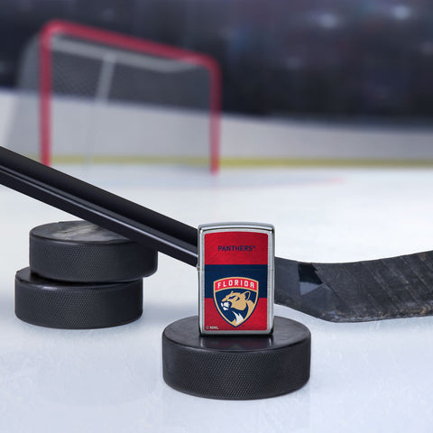 Lifestyle image of the NHL® Florida Panthers™ Street Chrome™ Windproof Lighter standing with a hockey puck and hockey stick, with a hockey net in the background.