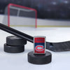 Lifestyle image of the NHL® Montreal Canadiens™ Street Chrome™ Windproof Lighter standing with a hockey puck and hockey stick, with a hockey net in the background.