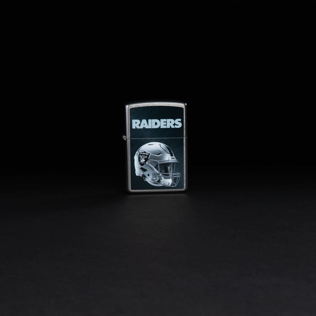 Lifestyle image of NFL Las Vegas Raiders Helmet Street Chrome Windproof Lighter standing in a black bacground.