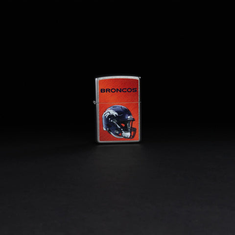 Lifestyle image of NFL Denver Broncos Helmet Street Chrome Windproof Lighter standing in a black background.