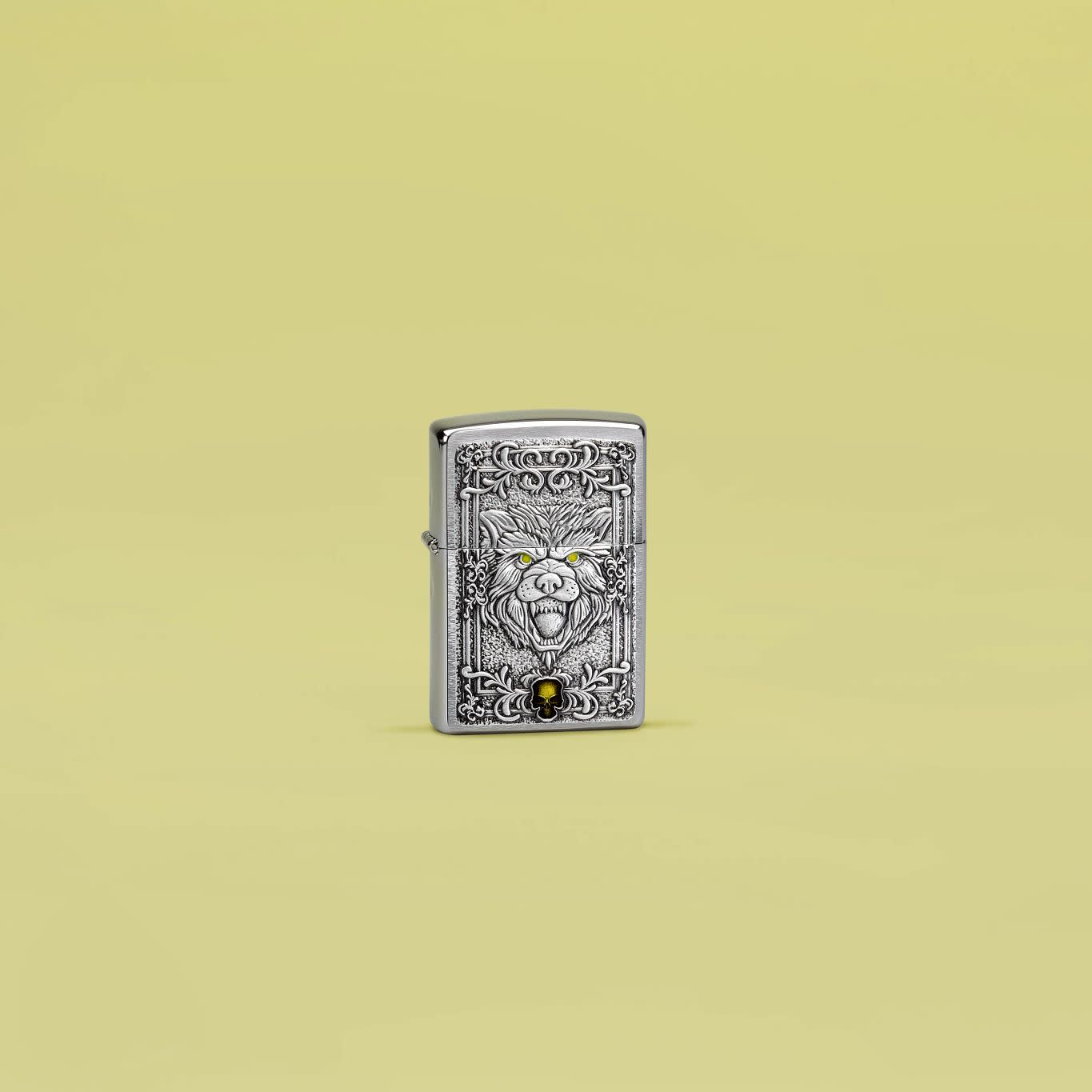 Lifestyle image of Zippo Wolf Emblem Design Brushed Chrome Windproof Lighter standing in a yellow scene.