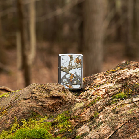 Lifestyle image of Realtree® Camo Logo Street Chrome™ Windproof Lighter standing on a log in the woods.