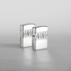 Lifestyle image of two Armor® Sterling Silver Diamond Pattern Design Windproof Lighters standing in a silver scene. One lighter is showing the front of the design with the second showing the back.