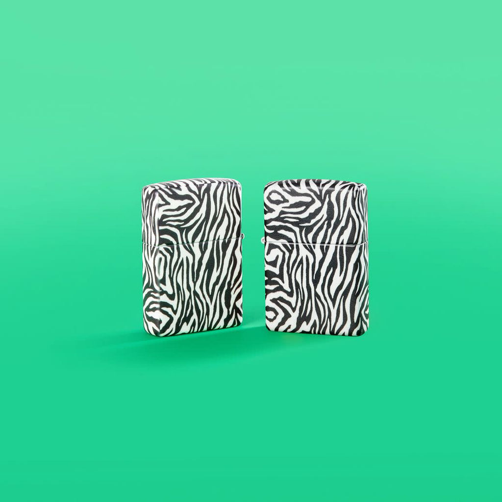 Lifestyle image of Zebra Print Design 540 Color Windproof Lighters standing in a green background.