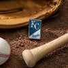 Lifestyle image of MLB® Kansas City Royals™ Street Chrome™ Windproof Lighter laying on a baseball field with a glove, ball, and bat.