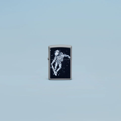 Lifestyle image of Zippo Skateboarding Astronaut Design Flat Grey Windproof Lighter standing in a grey scene.