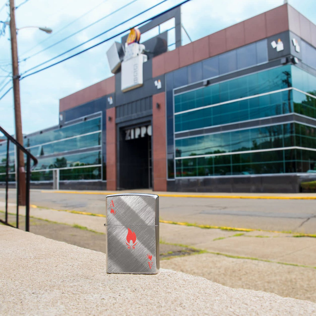 Lifestyle image of Flame Ace Design Diagonal Weave Windproof Lighter standing in front of the Zippo building.